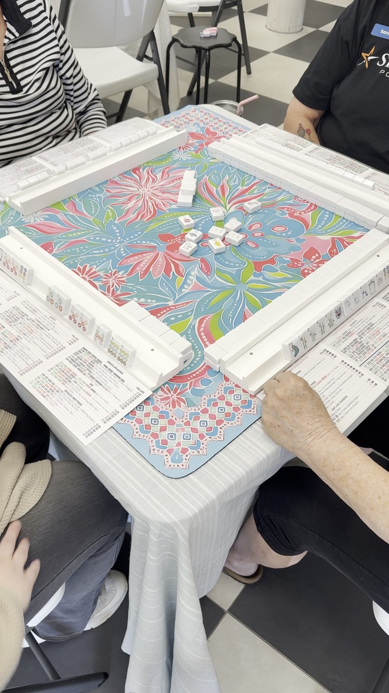 A mahjong game underway on a colorful floral mat