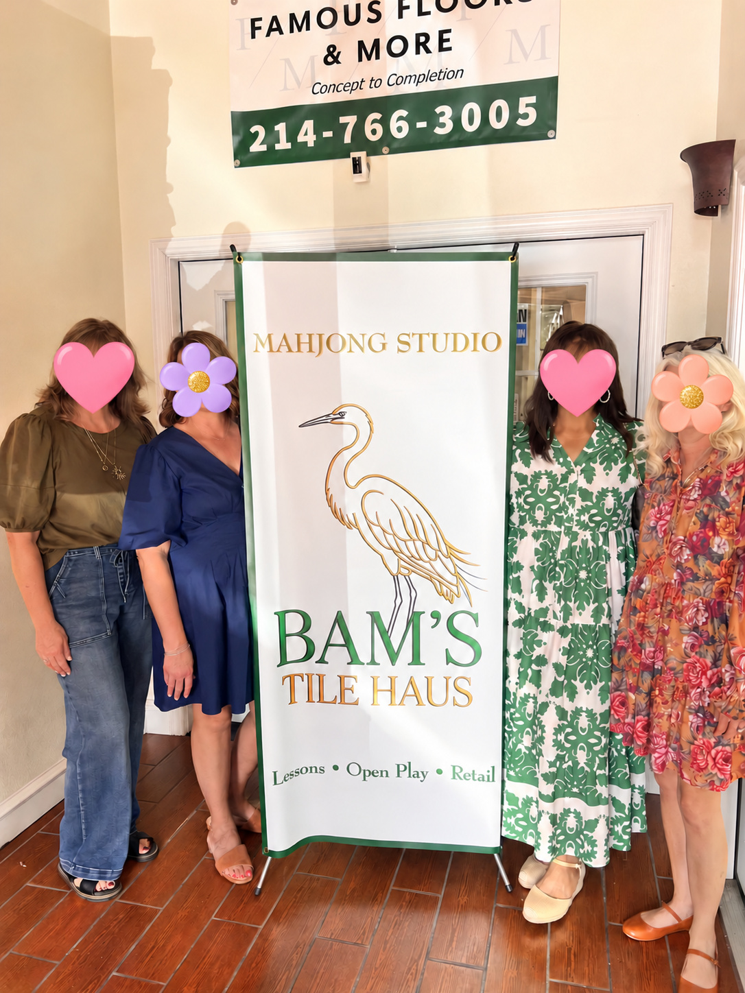 Four friends beside the Bam’s Tile Haus heron banner inside Famous Floors and More; faces covered with hearts and flowers