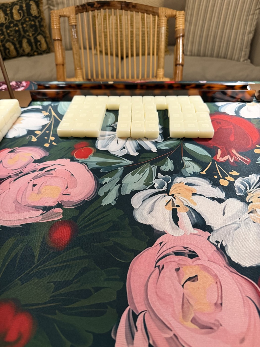 Mahjong tiles arranged on a floral mat beside a bamboo chair
